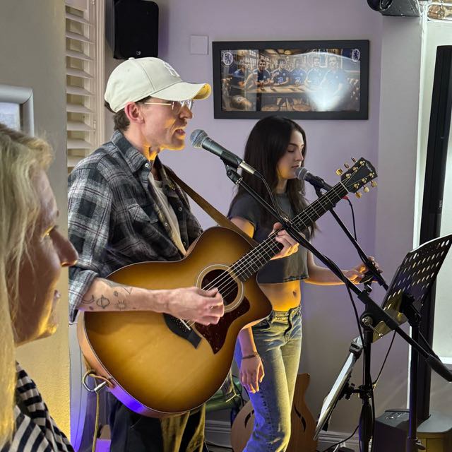 Guitarist performing at an open mic night with another singer