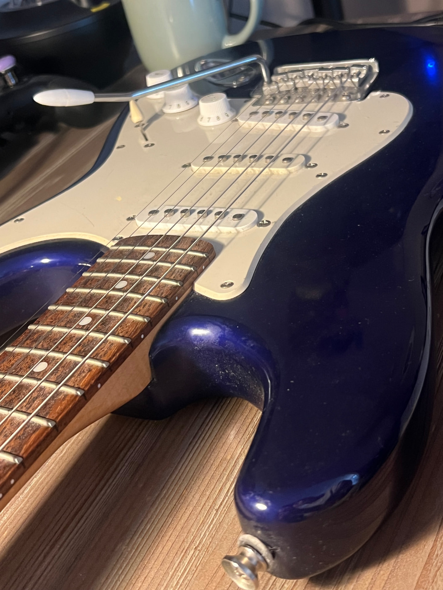 Close-up of a blue electric guitar with whammy bar and strings